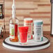 An OXO Good Grips Lazy Susan with a bottle of alcohol and a bottle of soda on it.