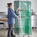 A woman standing in a kitchen with a Curtron green breathable mesh cover on a rack of food.