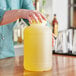 A person holding a large plastic container of yellow liquid.