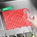 A person holding a glass over a red interlocking bar mat.