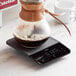 An OXO coffee scale with a glass jar of brown liquid on it.