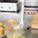 A Winco boar bristle pastry brush spreading butter on pastries in a container.