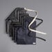 A stack of black denim Acopa Kennett aprons with black straps.