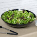 A black GET Siciliano bowl filled with green and red lettuce on a table.