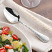 An Acopa Inspira stainless steel serving spoon in a bowl of pasta salad.
