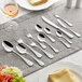 A table with Acopa Vittoria stainless steel spoons and forks set on it.