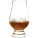 A glass of brown liquid with Outset white marble whiskey stones in it.