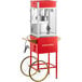 A red and white Carnival King commercial popcorn machine with wheels.