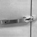 A metal handle on a white wall above a stainless steel door.