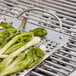 A stainless steel Outset grill tray with green vegetables on it.