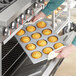 A person putting jumbo muffins in a Baker's Mark jumbo muffin pan.