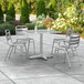 A Lancaster Table & Seating chrome square outdoor table with four silver chairs on a patio.