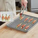 Baker's Mark aluminum sheet pan with stainless steel footed cooling rack holding bacon-wrapped celery on a rack.