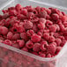 A plastic container of IQF raspberries on a white background.