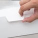 A hand opening a white window cupcake box with a white insert.