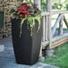 A black Mayne Kobi planter with flowers in it.