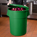 A person holding a green 55 gallon ingredient storage bin full of onions.