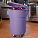 A person holding a purple 55 gallon mobile ingredient storage bin.