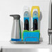 An OXO Good Grips sink organizer holding cleaning tools and a sponge on a kitchen counter.