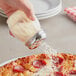 A Tablecraft clear plastic shaker with a chrome-plated top being used to sprinkle white powder onto a pepperoni pizza.