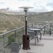 A Flash Furniture bronze metal outdoor patio heater on a table on an outdoor patio with chairs.