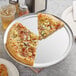 A pizza on a Choice aluminum pizza pan with a slice missing.