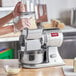 A woman using an Estella electric cheese grater to slice cheese.