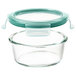 An OXO clear glass round container with a green leakproof lid.