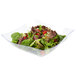 A clear plastic Fineline serving bowl filled with salad with tomatoes and lettuce.