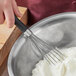 A hand using an OXO Good Grips narrow whisk in a bowl of whipped cream.