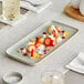 A rectangular white Acopa porcelain platter with strawberries and whipped cream on it.