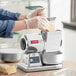 A woman using an Estella electric hard cheese grater to grind cheese.