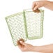 A hand holding a green rectangular plastic basket with a grid inside.