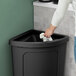 A hand using a white towel to clean a Lavex black trash can lid.