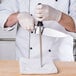 A person in white gloves using a Mercer Genesis Forged Sharpening Steel to sharpen a knife.