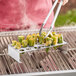 A person grilling jalapenos in a Tablecraft stainless steel jalapeno roaster on a grill.