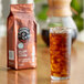 A glass of Lavazza Tierra! Brasile Coarse Ground Coffee with ice and a bag of coffee on a table.