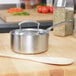 A Vollrath stainless steel saucepan on a wooden surface.