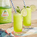 A pair of green drinks made with Jarritos Lime Slushy Concentrate with lime slices.