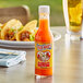 A bottle of Marie Sharp's Garlic Habanero Hot Sauce on a table with tacos.