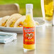 A close up of a bottle of Marie Sharp's Pineapple Habanero hot sauce on a table with tacos.