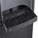 A black Follett air cooled ice maker and water dispenser with a black grate over a black container.