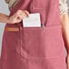 A woman wearing an Acopa Hazleton wine canvas apron with pockets at a restaurant counter.