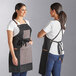 Two women wearing Backyard Pro charcoal aprons with different designs.