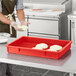 A person wearing gloves in a kitchen using a red Baker's Mark dough proofing box to hold dough.
