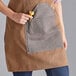 A woman wearing a brown Backyard Pro grilling apron with a pocket.
