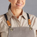 A woman wearing an Acopa Hazleton apron with brown cross-back straps.