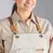 A woman wearing a restaurant apron with mocha leather cross-back straps.