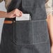 A woman wearing a black Acopa canvas bib apron with three pockets.