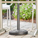 A black Lancaster Table & Seating umbrella base on a table in an outdoor patio.